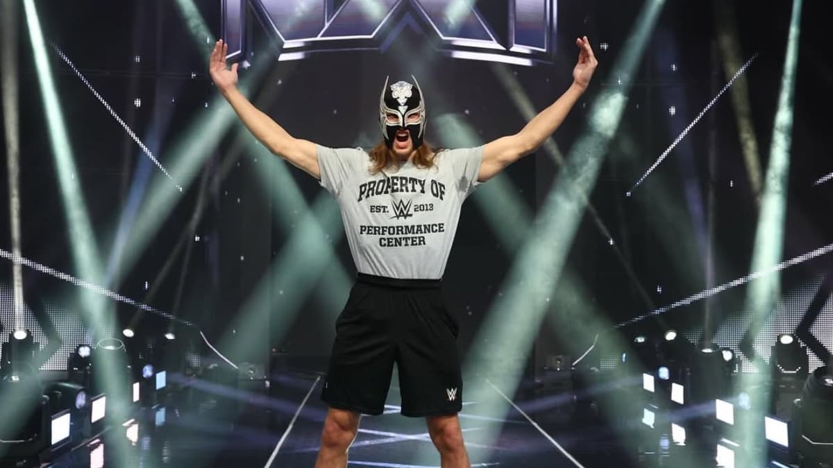 Elio LeFleur wearing a WWE Performance Center t-shirt in front of NXT logo