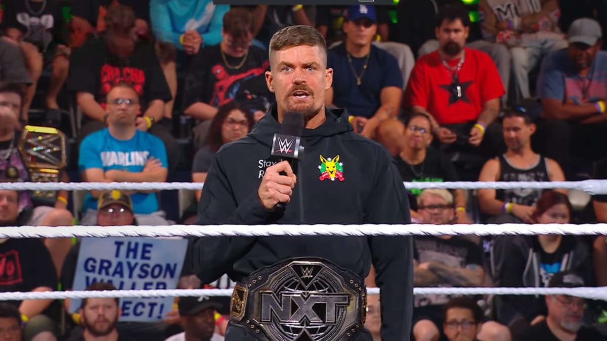 Grayson Waller wearing a black hoodie with the NXT Title around his waist