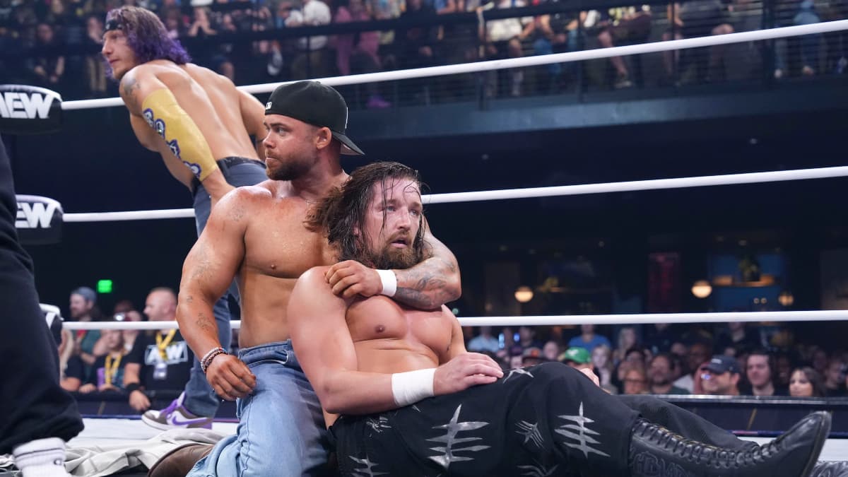 Jay White sits dazed in a wrestling ring with Austin Gunn, as Ace Austin watches on in the background.