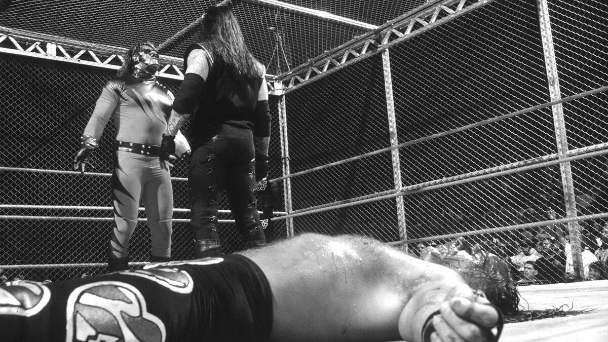 Kane and The Undertaker staring at each other as a bleeding Shawn Michaels lies down