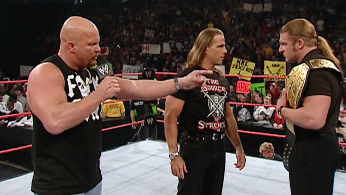 Steve Austin pointing at Triple H as Shawn Michaels and Triple H stare at each other inside the WWE Raw ring