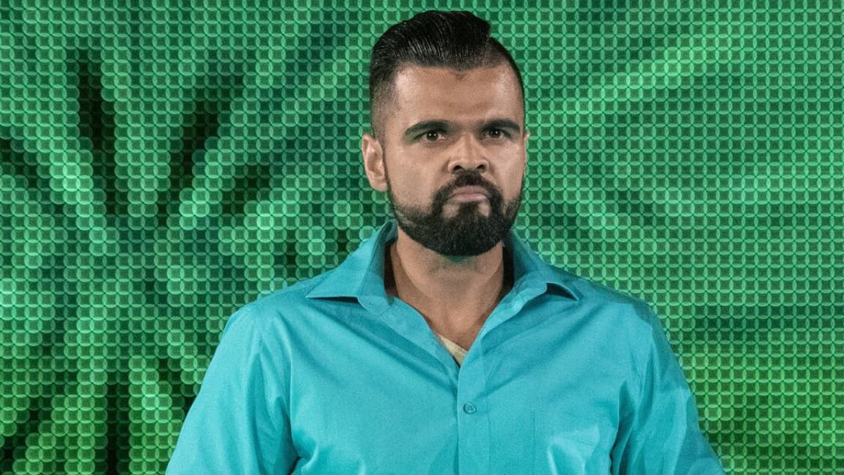 Sunil SIngh in a turquoise shirt walking down a WWE entrance ramp