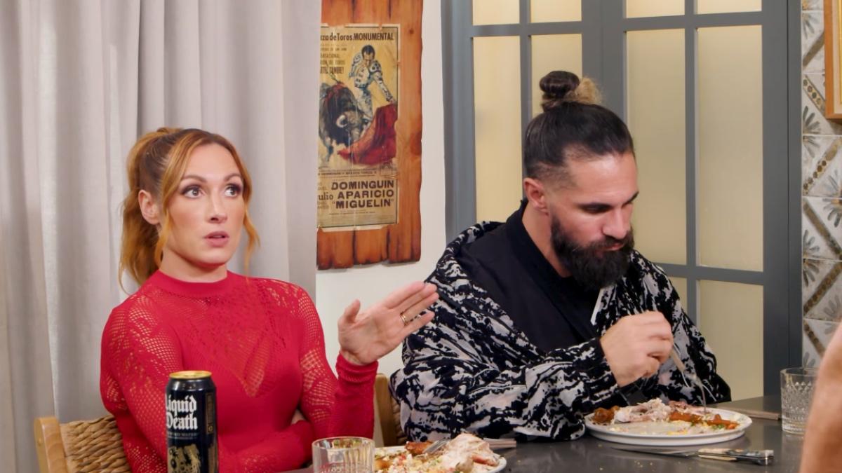 Becky Lynch pointing as Seth Rollins eats 
