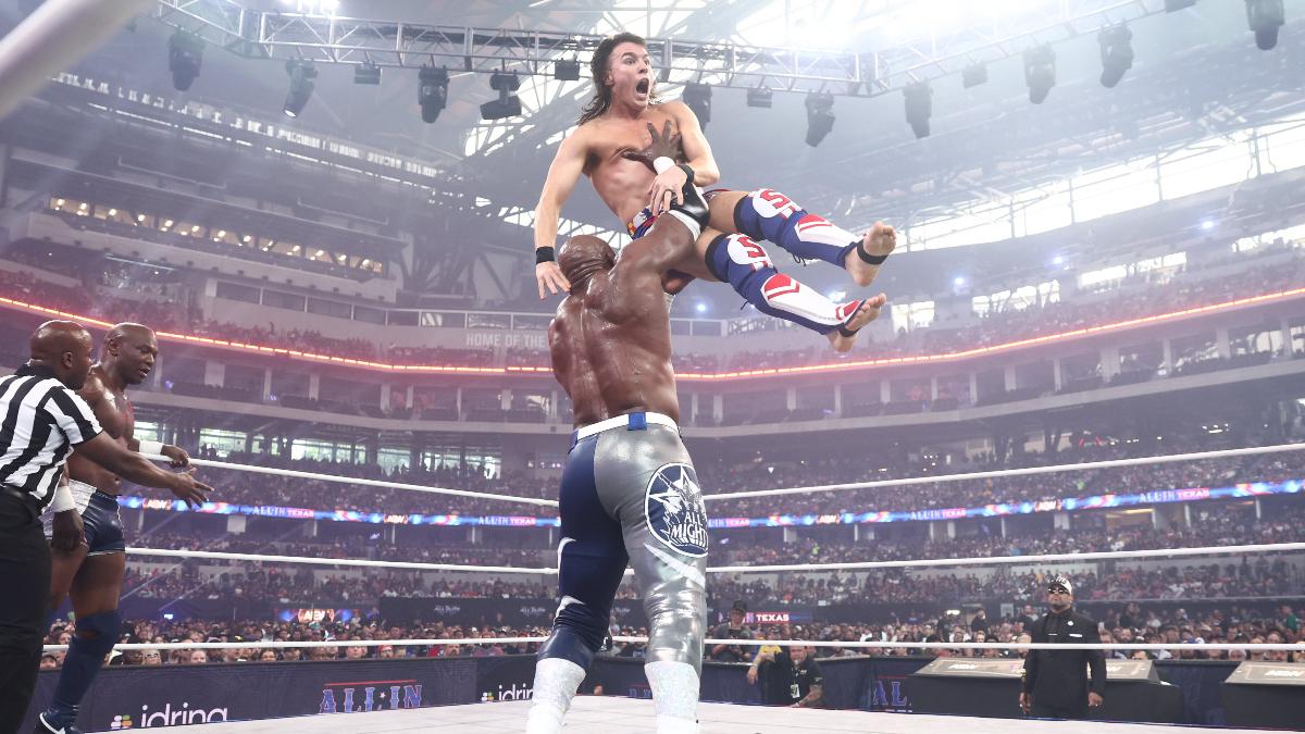 Bobby Lashley lifts up Mike Bailey for a big chokeslam in an AEW ring as Shelton Benjamin watches on from the side
