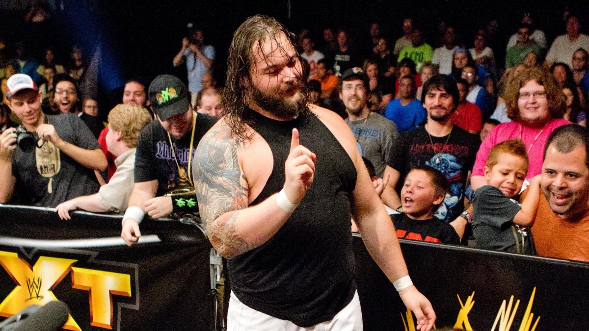 Bray Wyatt in his WWE NXT debut wagging his finger while wearing a black vest and white pants
