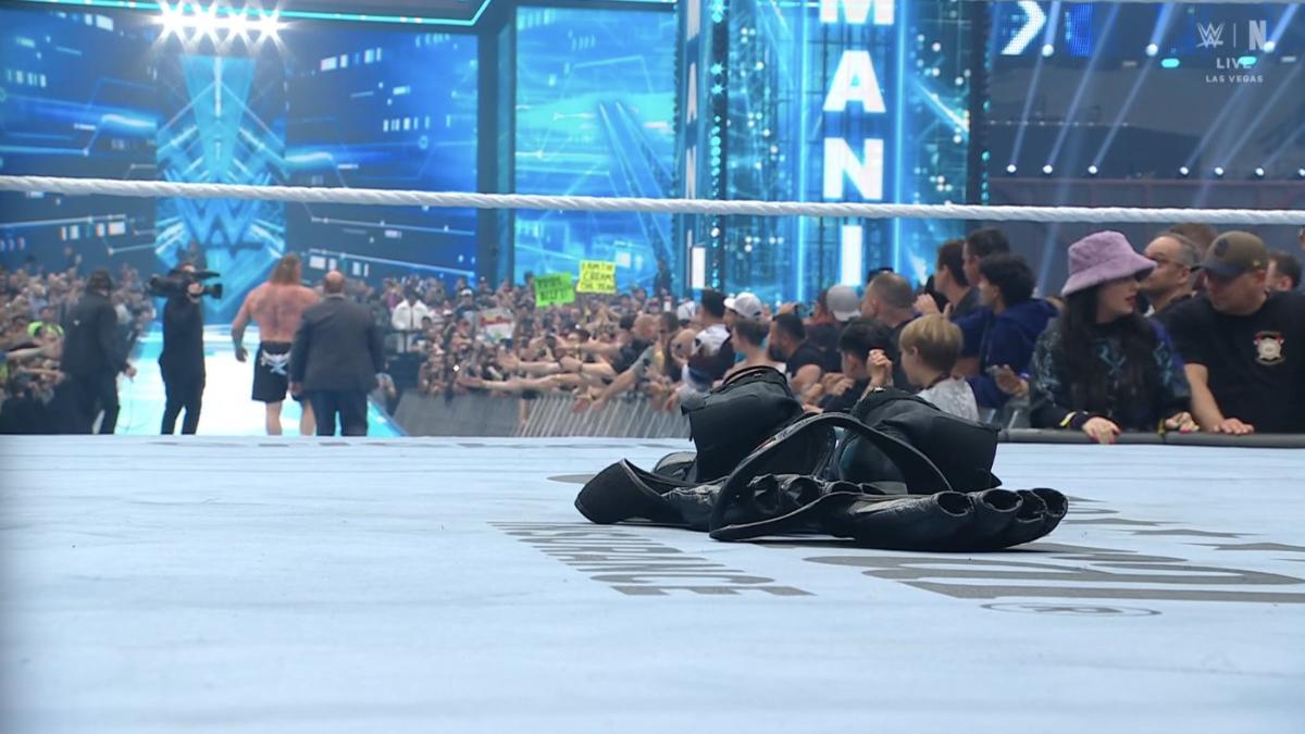 Brock Lesnar's gloves and boots in the ring at WWE WrestleMania 42 as Lesnar and Paul Heyman walk up the ramp in the distance