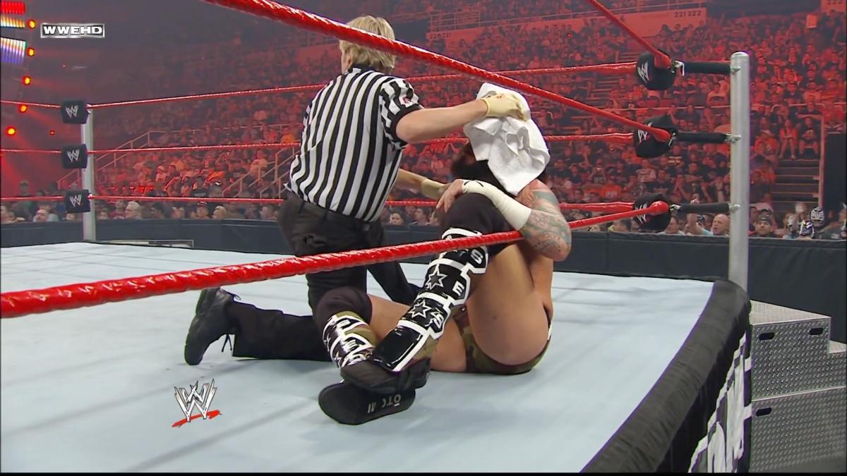 Charles Robinson holding a towel over CM Punk's head over Over The Limit 2010