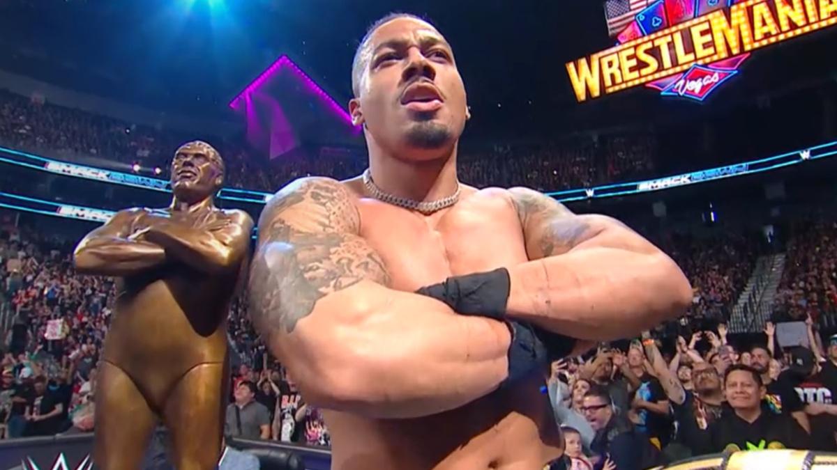 Carmelo Hayes posing next to Andre The Giant Memorial Trophy 
