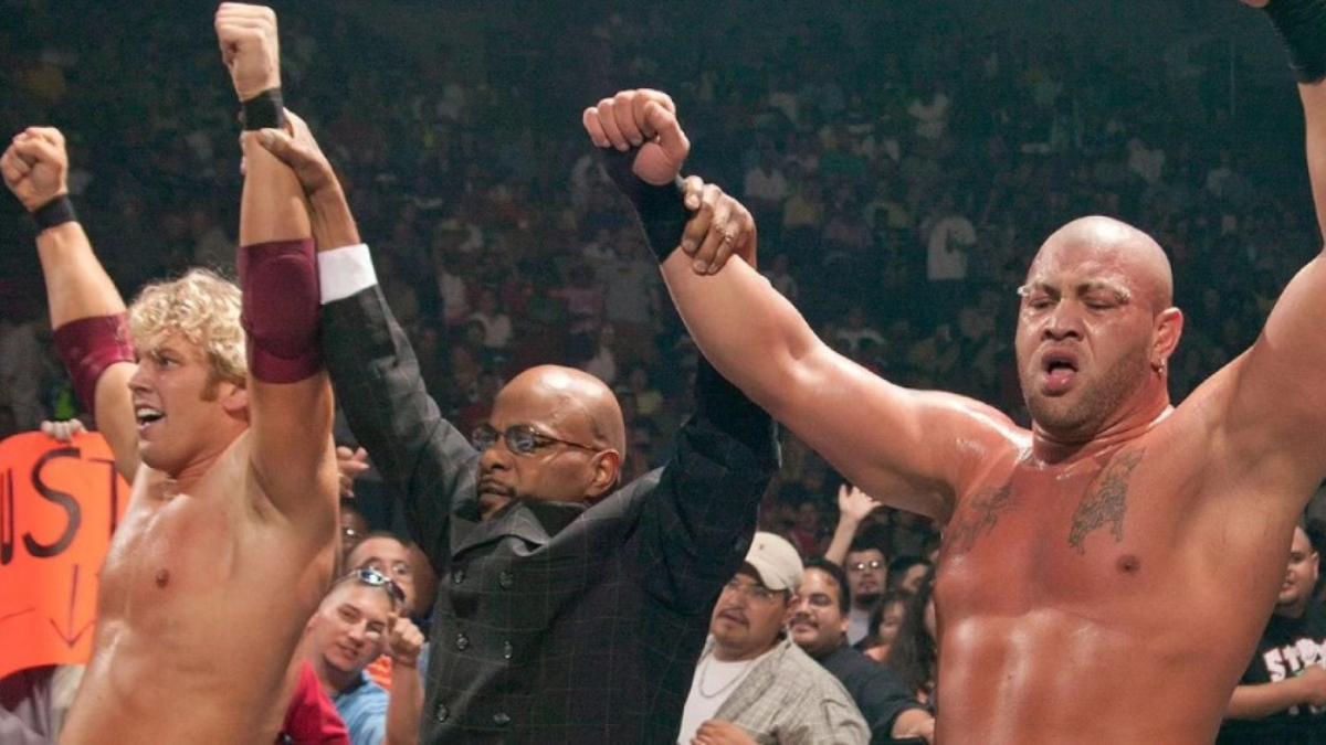 Teddy Long holding up the arms of Christopher Nowinski and Rodney Mack in 2002