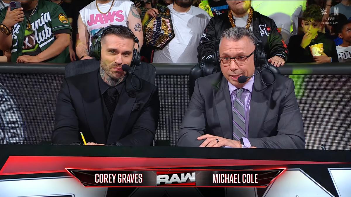 Corey Graves sitting alongside Michael Cole, with both wearing suits, on WWE Raw