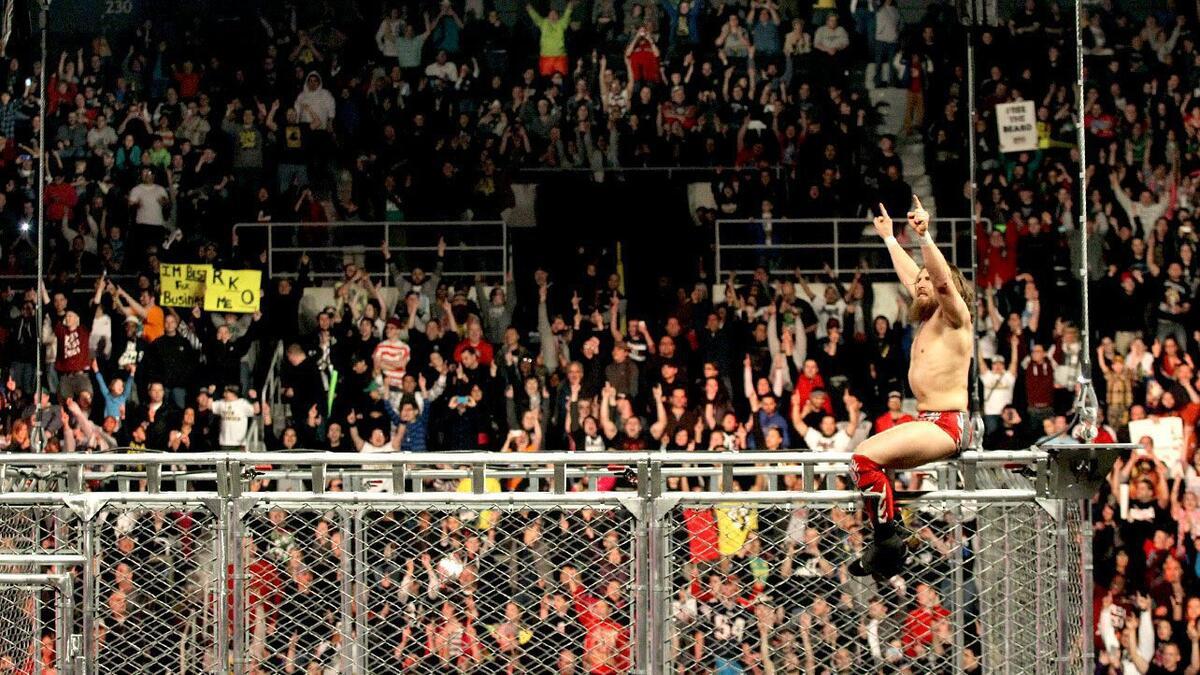 Daniel Bryan hitting on top of a steel cage leading the crowd in YES! chants
