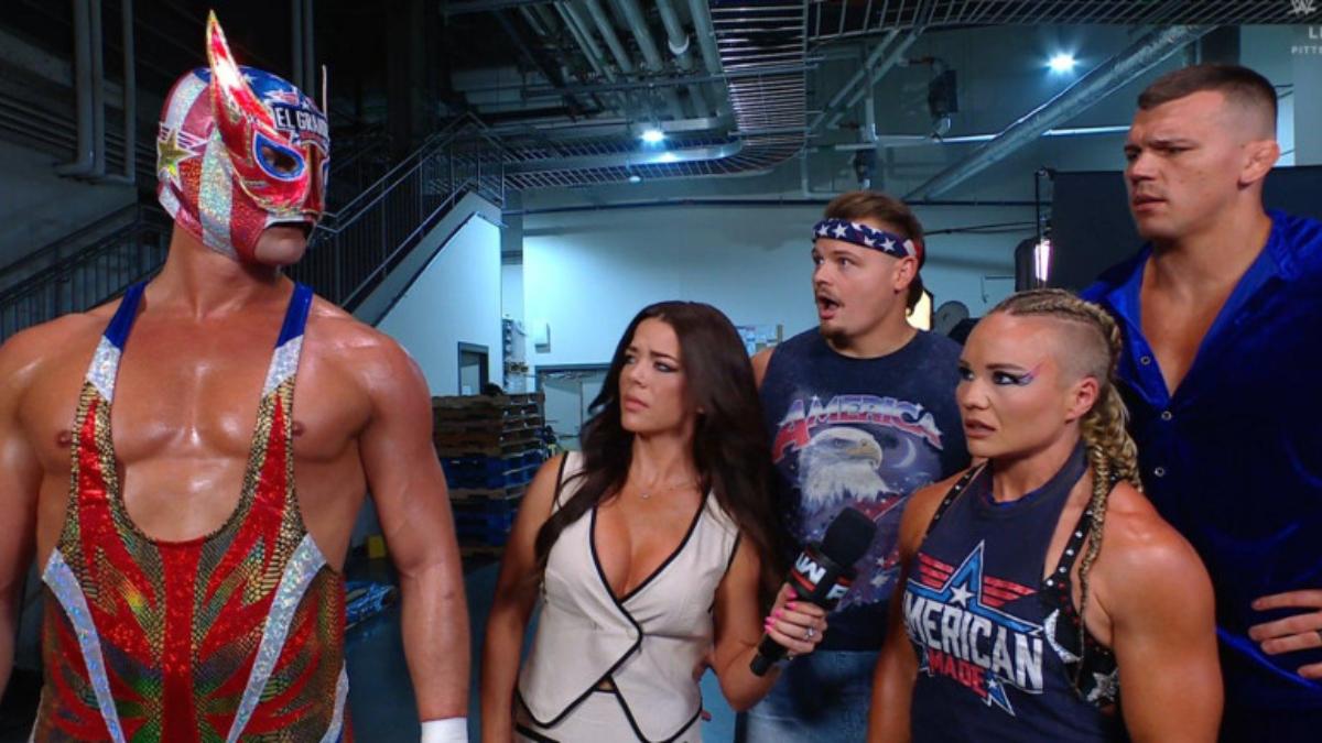 El Grande Americano backstage at a WWE event with Jackie Redmond and American Made looking back in shock and confusion