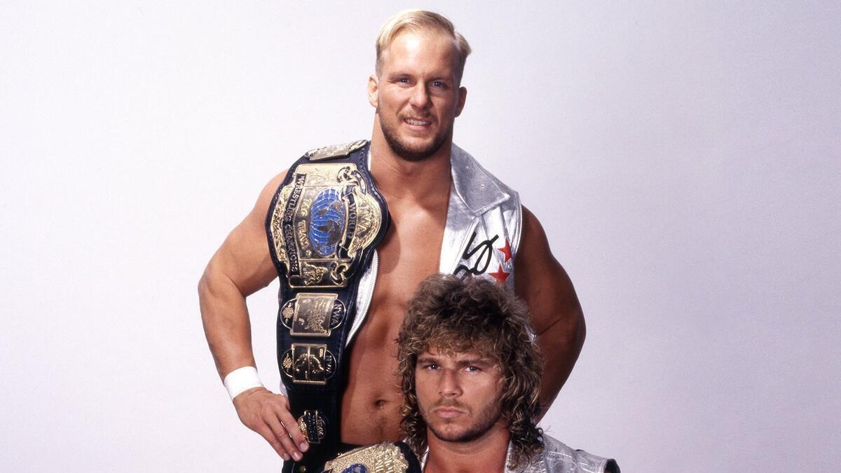 Steve Austin stood above Brian Pillman as they hold the WCW World Tag Team Titles in a photoshoot