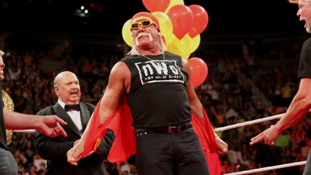 Hulk Hogan taking a jacket off with red and yellow balloons behind him 