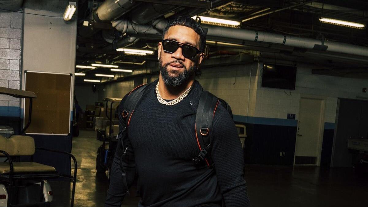 Jey Uso walking with a black jumper and sunglasses