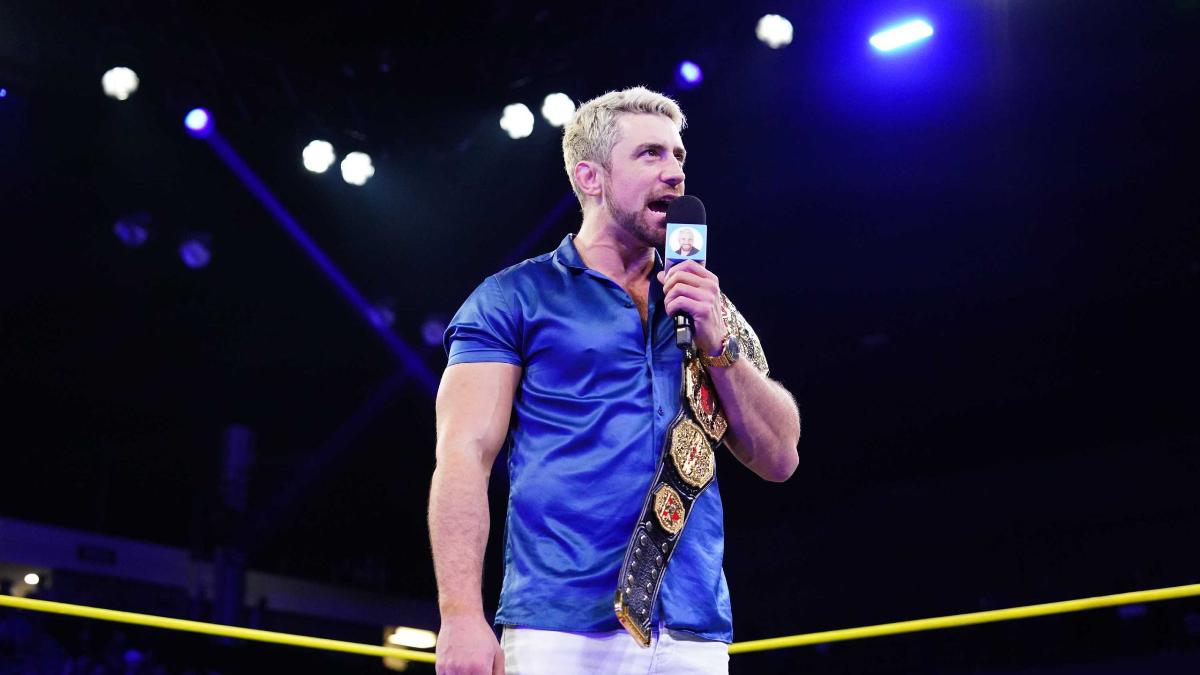 Joe Hendry cutting a promo on April 2025 episode of TNA IMPACT wearing a blue satin shirt and white trousers with TNA World Title over his shoulder