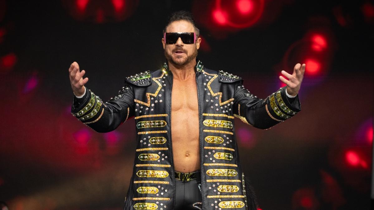 Johnny TV wearing sunglasses and a black and gold trench jacket