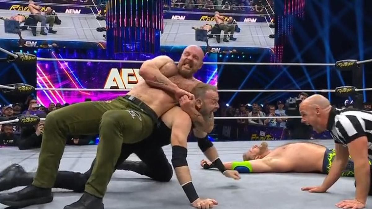 Jon Moxley locks the bulldog choke on Christian Cage in front of a referee as Cope lays unconscious in the background in the ring at AEW Revolution 2025,
