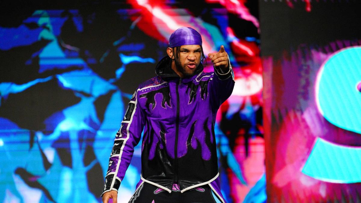 Leon Slater in purple attire pointing