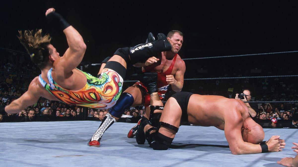 Rob Van Dam hitting a dropkick to Kurt Angle while Steve Austin crawls next to them in 2001