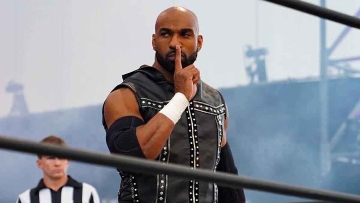 Scorpio Sky in a wrestling ring pressing his index finger against the side of his nose whilst looking to the side