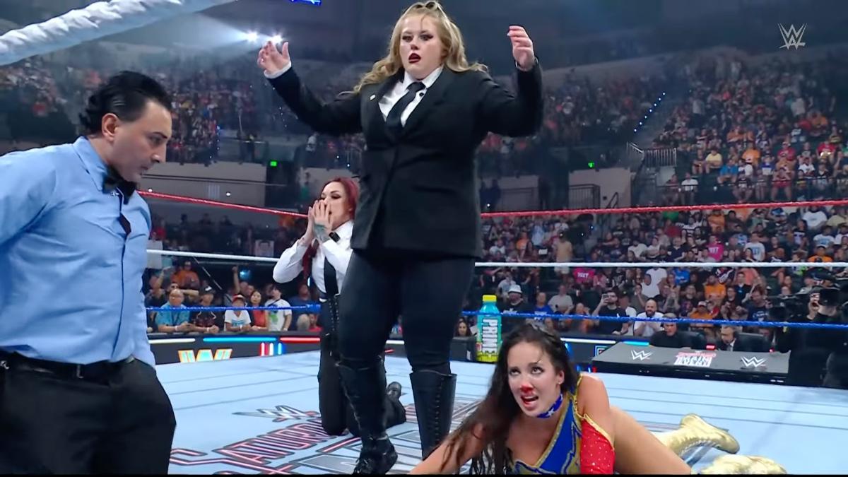 Piper Niven looking upset standing up as Chelsea Green crawls down with a bleeding nose