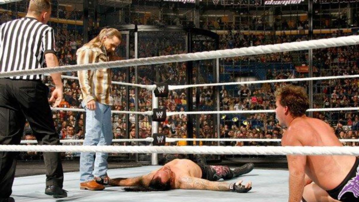 Shawn Michaels standing above a down Undertaker as Chris Jericho looks on shocked at WWE Elimination Chamber 2010