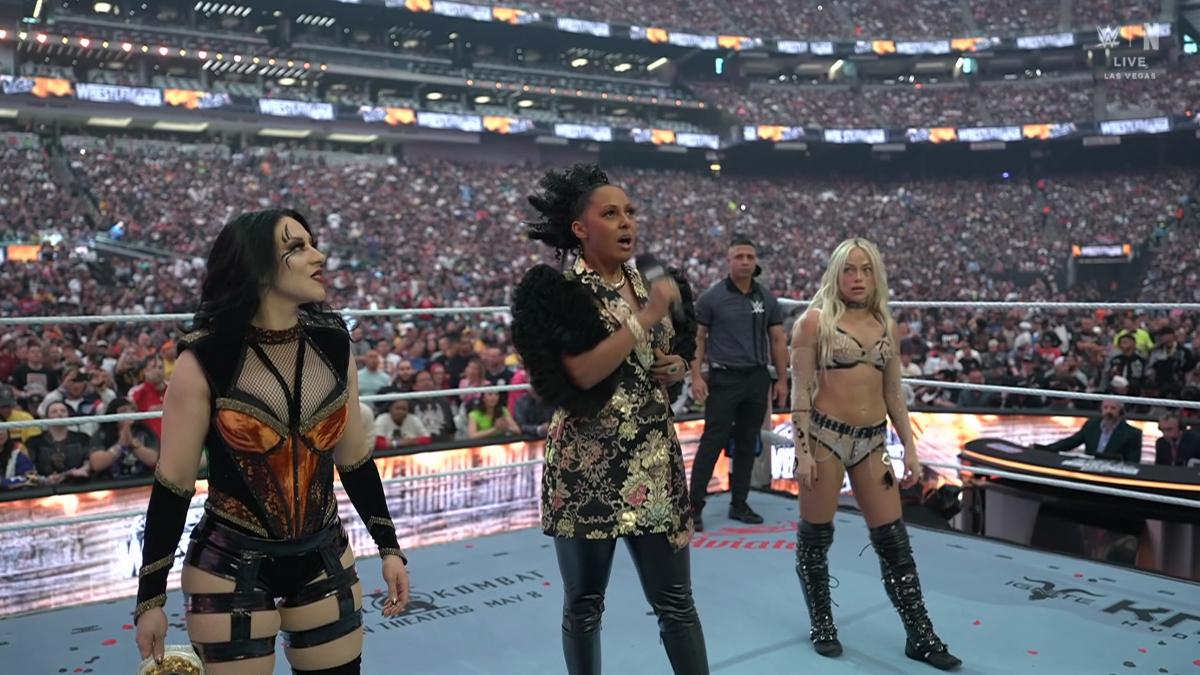 Stephanie Vaquer and Liv Morgan standing in the ring for their introductions at WrestleMania 42 with Alicia Taylor in the middle