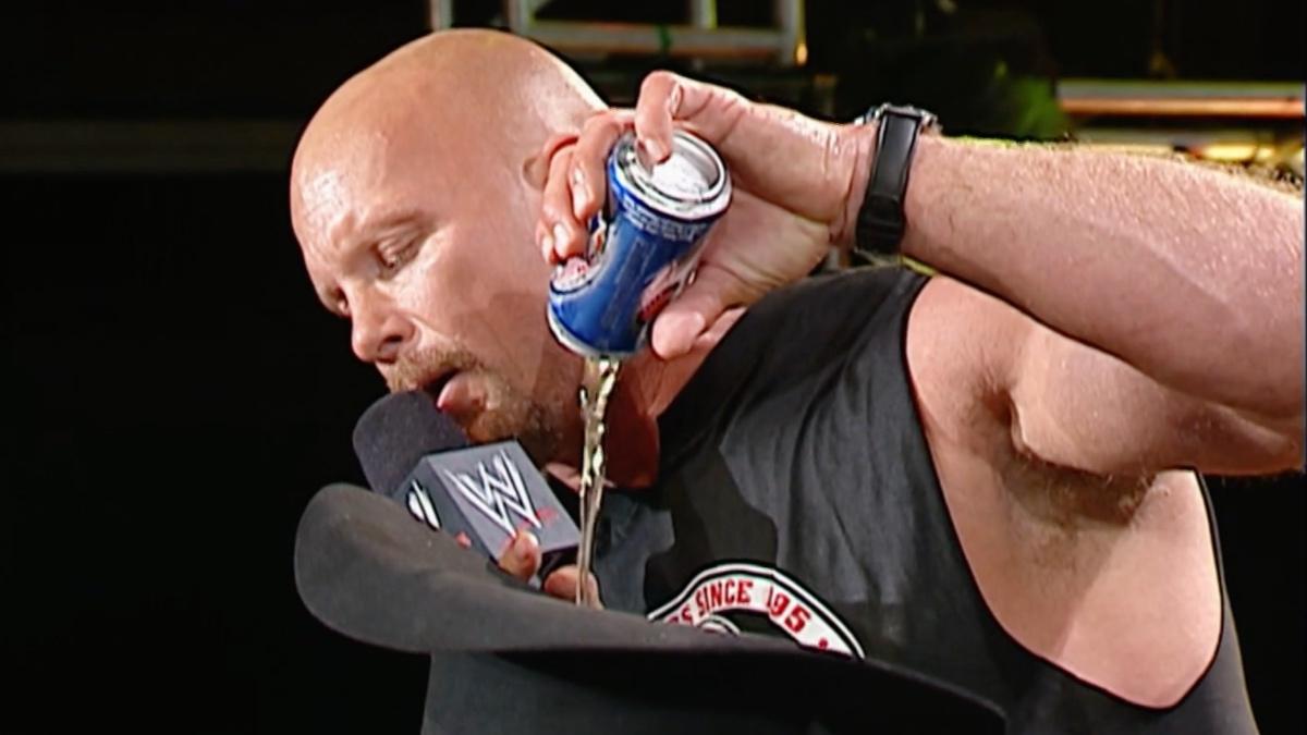 Steve Austin pouring beer into Jonathan Coachman's hat