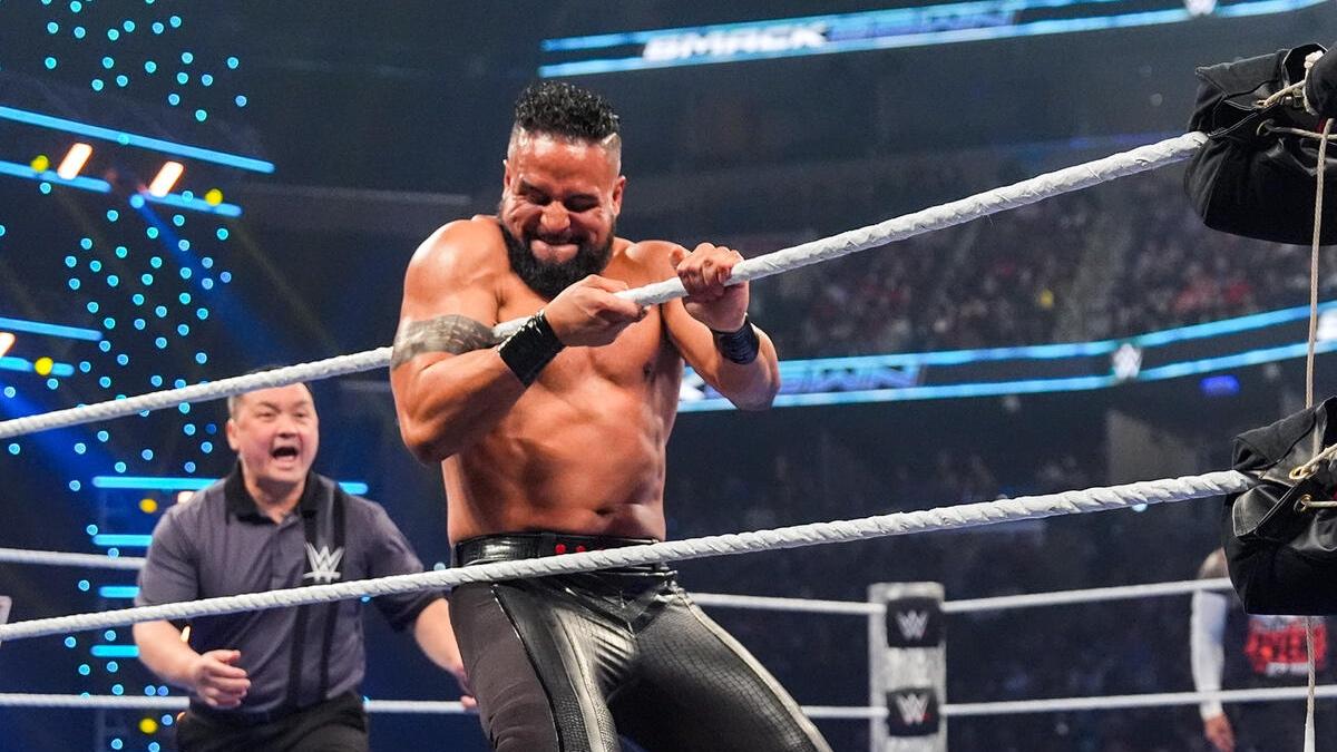Tama Tonga grimacing while grabbing the ring ropes on WWE SmackDown