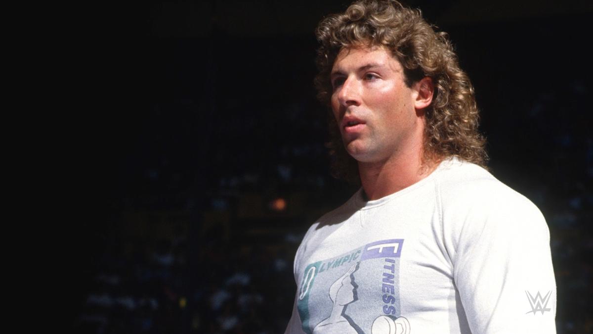 Tom Magee wearing a white t-shirt in pro wrestling ring