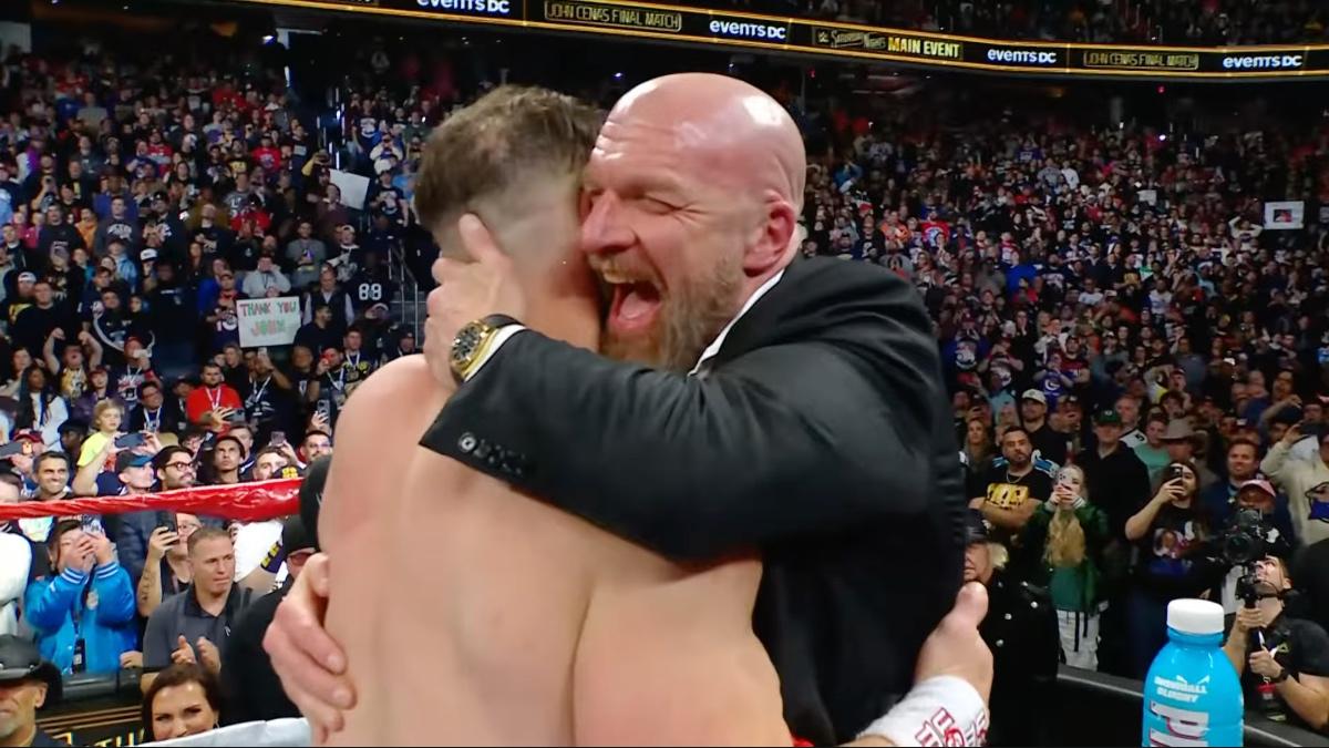 Triple H laughing while hugging John Cena following Cena's retirement match