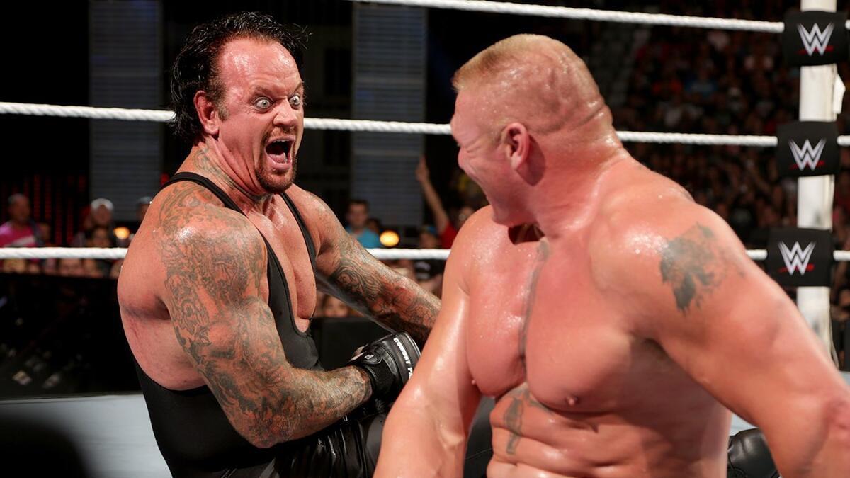 Brock Lesnar and The Undertaker laughing at each other while sat down in the ring at WWE SummerSlam 2015