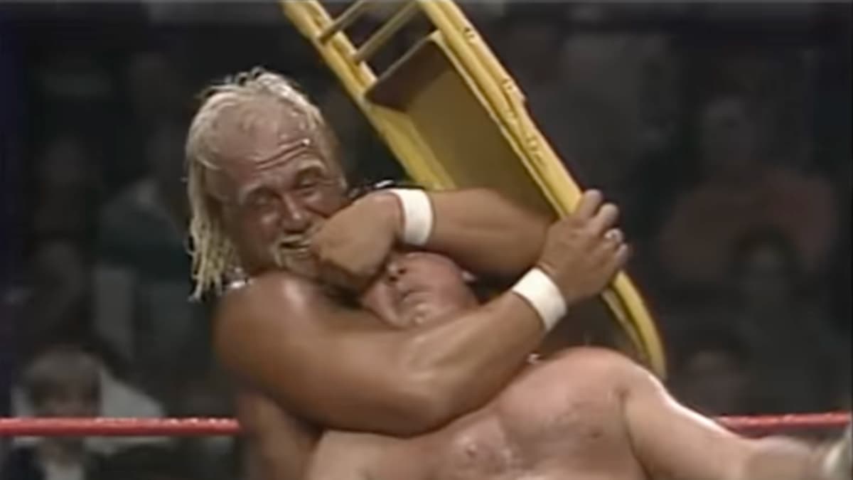 Hulk Hogan with a sleeper on Roddy Piper while holding a yellow steel chair at WWF The Wrestling Classic