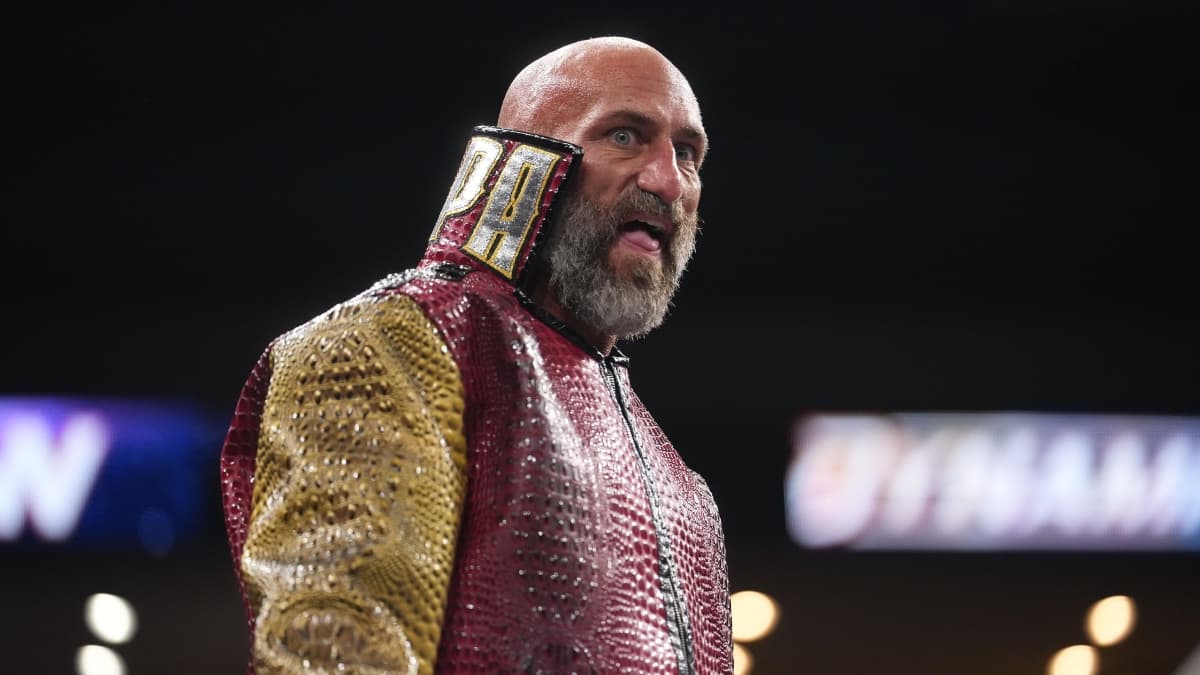 Tommaso Ciampa with his little tongue out wearing a red and gold jacket