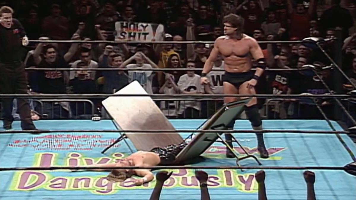 Mike Awesome standing to the side in the ring as Kid Kash lies in a heap in the middle of a broken table