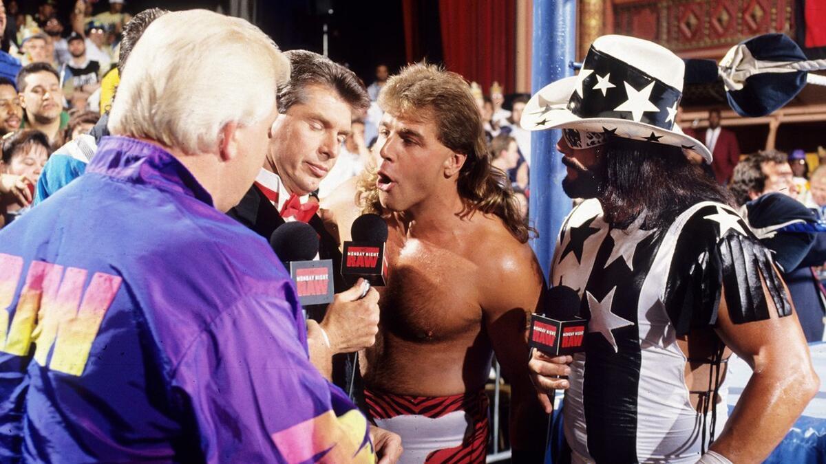 Shawn Michaels shouting into a microphone while being interviewed by Vince McMahon, Bobby Heenan, and Randy Savage at ringside on a 1993 episode of WWE Raw