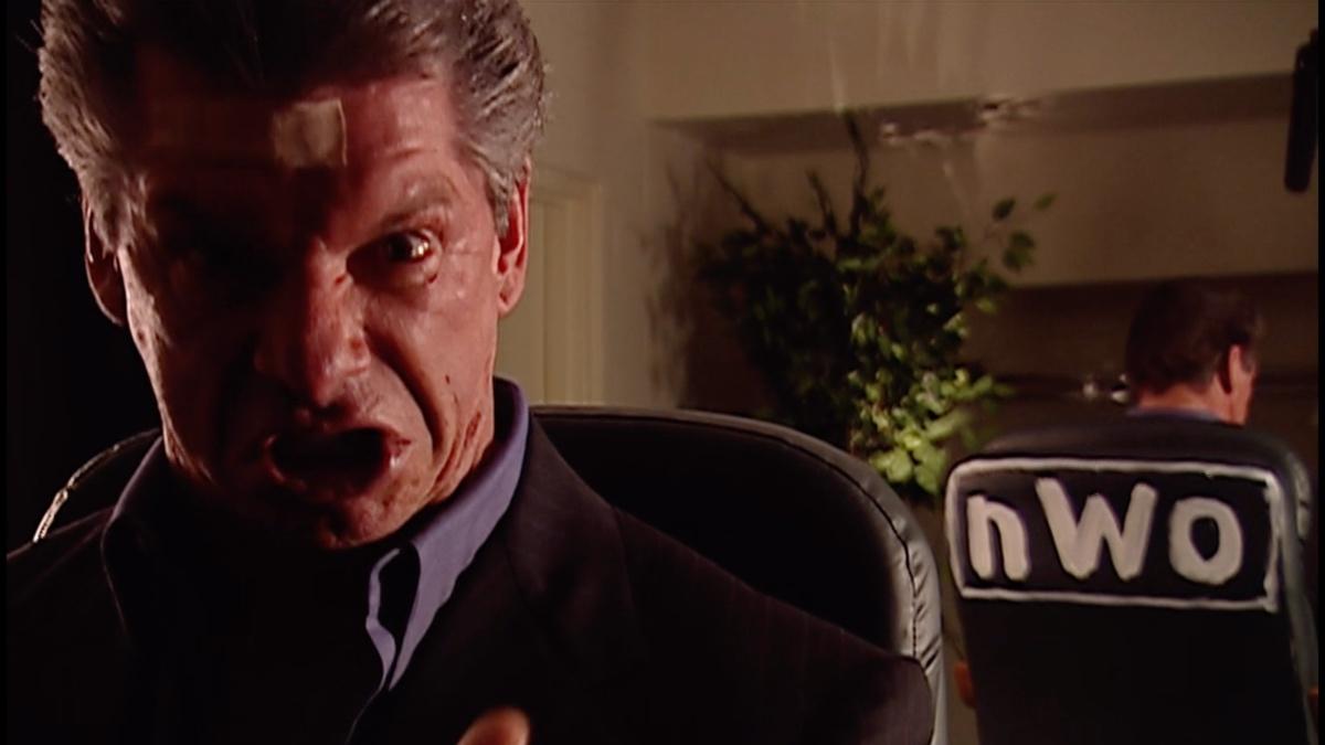 Vince McMahon being expressive as 'NWO' is shown on the back of his chair